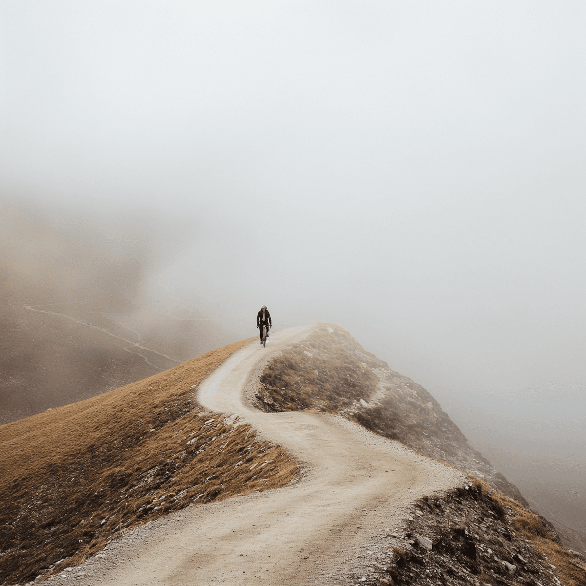 Solitary cyclist on a misty ridge trail